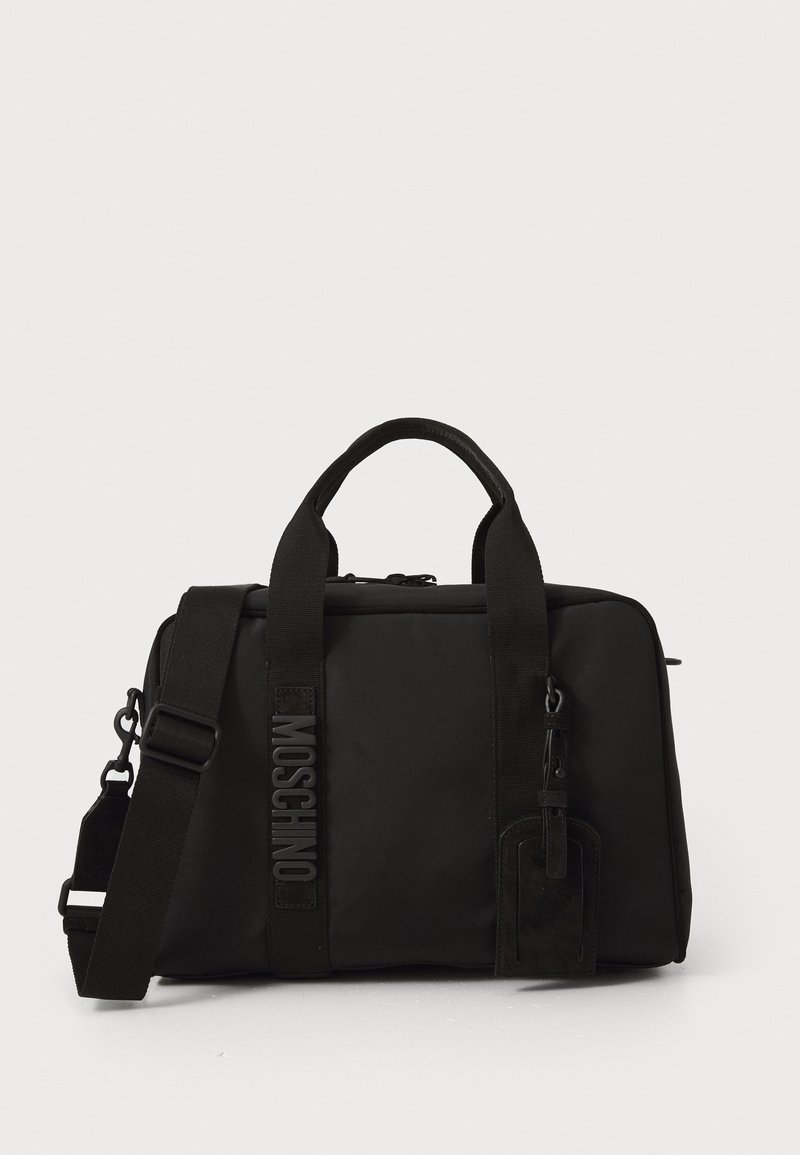 Sac textil negru cu mânere duale și curea de umăr detașabilă. Prezintă un logo embosat și o etichetă din piele. Textură netedă, formă dreptunghiulară.
