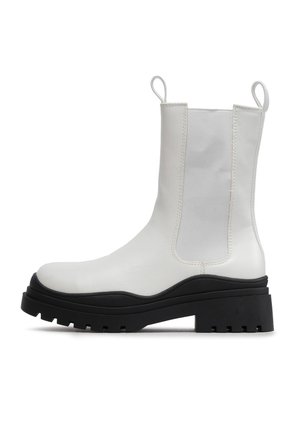 Weißer Leder-Stiefelette mit schwarzer klobiger Sohle, elastischem Seiteneinsatz und Zuglaschen vorne und hinten.