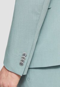 Lichtblauw colbertjasje met vier grijze knopen en een gestructureerde stofafwerking. Getailleerde pasvorm met nette stikdetails.