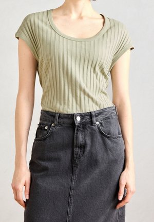 Person wearing a light green ribbed short-sleeve top tucked into a high-waisted black denim skirt with front pockets and button closure.