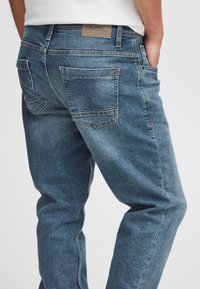 Blå jeans i denim med rak skärning, utrustade med två bakfickor och en märkesläderlapp på midjebandet. Slät textur, blekt utförande.