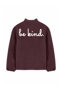 Giacca in pile viola scuro con tessuto strutturato e la scritta "be kind." in grandi lettere corsive bianche sulla parte superiore della schiena.