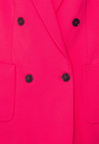 Felroze dubbelgeknoopte blazer met zwarte knopen en voorzakken, op maat gemaakt met een klassieke kraag en revers.