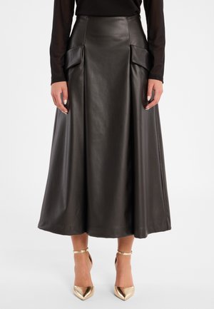 Zwarte leren midi-rok met een hoge taille, voorplichtingen en twee grote zakken. Gecombineerd met glanzende gouden puntige hakken.
