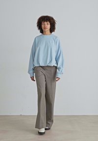 Lys blå oversized sweatshirt, grå vide bukser og sorte platform sko. Glatte teksturer med en afslappet pasform og minimalistisk design.
