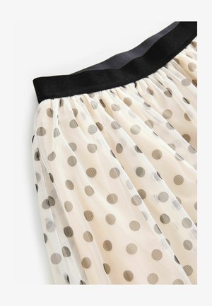 Tulle skirt in cream with black polka dots, featuring a wide black waistband. Semi-sheer texture with layered design and soft drape.