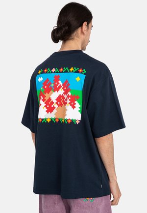 Camiseta de algodón azul marino con un gran diseño de pieza de rompecabezas colorida en la parte posterior, con flores y una escena paisaje. Corte holgado, mangas cortas.
