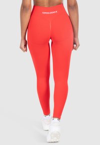 Rode high-waisted leggings van een gladde, rekbare stof. Heeft een wit logo op de achterzijde van de tailleband en een aangesloten ontwerp dat de benen accentueert.