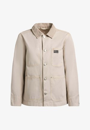 Bézs gombos dzseki kordbársony gallérral, három elülső foltzsebbel, hosszú ujjakkal és egy kis márkajelzéssel a bal mellzsebén.