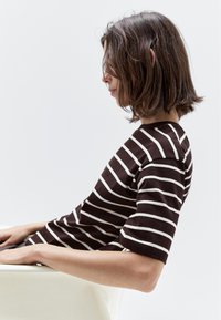 Brun og hvidstribet t-shirt med korte ærmer og rund halsudskæring, der har en afslappet pasform og blødt, struktureret stof.