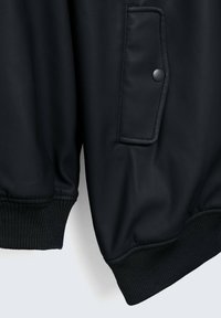 Veste bomber noire en cuir lisse, dotée d'une poche à bouton-pression et de poignets côtelés, mettant en valeur un design élégant et moderne.