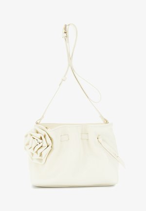Mała kremowa torebka z ozdobą w formie róży z przodu oraz regulowanym paskiem na ramię z elementami w złotym kolorze.