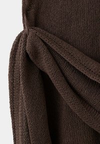 Gros plan d'un tissu tricoté marron foncé avec un détail de nœud texturé reliant deux sections.