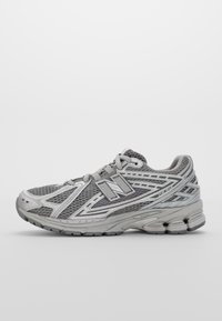 Grå sportskor med övre del i mesh, texturerad design och reflekterande detaljer. Har flexibel sula och vadderad häl för stöd.