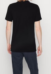 Czarny bawełniany t-shirt z okrągłym dekoltem i krótkimi rękawami, wyświetlany od tyłu. Gładka faktura i minimalistyczny design.