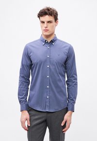 Modrá košeľa s dlhými rukávmi na gombíky s golierom, bielymi gombíkmi a malým vyšívaným logom na hrudi. Hladký bavlnený materiál.