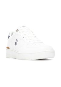 Zapatilla de piel blanca con puntera redonda, suela plana y detalles perforados. Presenta acentos en color marino y la marca 'TS 89' en el lateral.