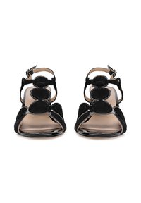 Sandalias negras con acabado de ante, que presentan un diseño de tira recta, acentos circulares, correas en el tobillo y una suela transparente.