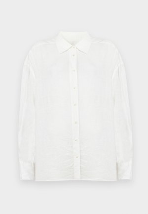 Chemise blanche en lin à manches longues avec fermeture boutonnée, col classique et coupe légèrement oversize, confectionnée dans un tissu texturé.