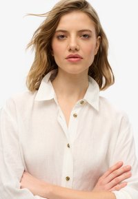 Witte linnen shirt met een kraag, met zichtbare knopen en opgerolde mouwen. Soepele textuur met een ontspannen pasvorm.