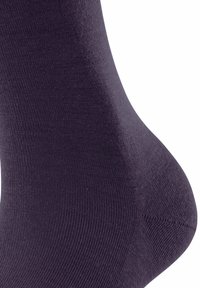 Primo piano di una calza viola scuro, che mette in evidenza la fine texture del tessuto a maglia e la morbidezza del materiale, evidenziando i contorni nella zona del tallone e della caviglia.