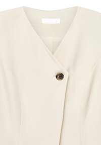 Cream-colored wrap blouse with a single dark tortoiseshell button near the V-neck collar and subtle seam detailing.