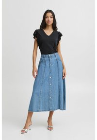 Melna V-veida maigā blūze ar īsām ruffles piedurknēm, pārī ar pogājamu A-line džinsa svārku gaiši zila krāsā. Modelis valkā sudraba papēža sandales.