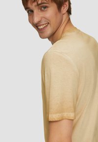 Helles gelbes Baumwoll-T-Shirt mit regulärer Passform, Rundhalsausschnitt und kurzen Ärmeln. Weiche Textur mit einem subtilen, leicht verwaschenen Finish.