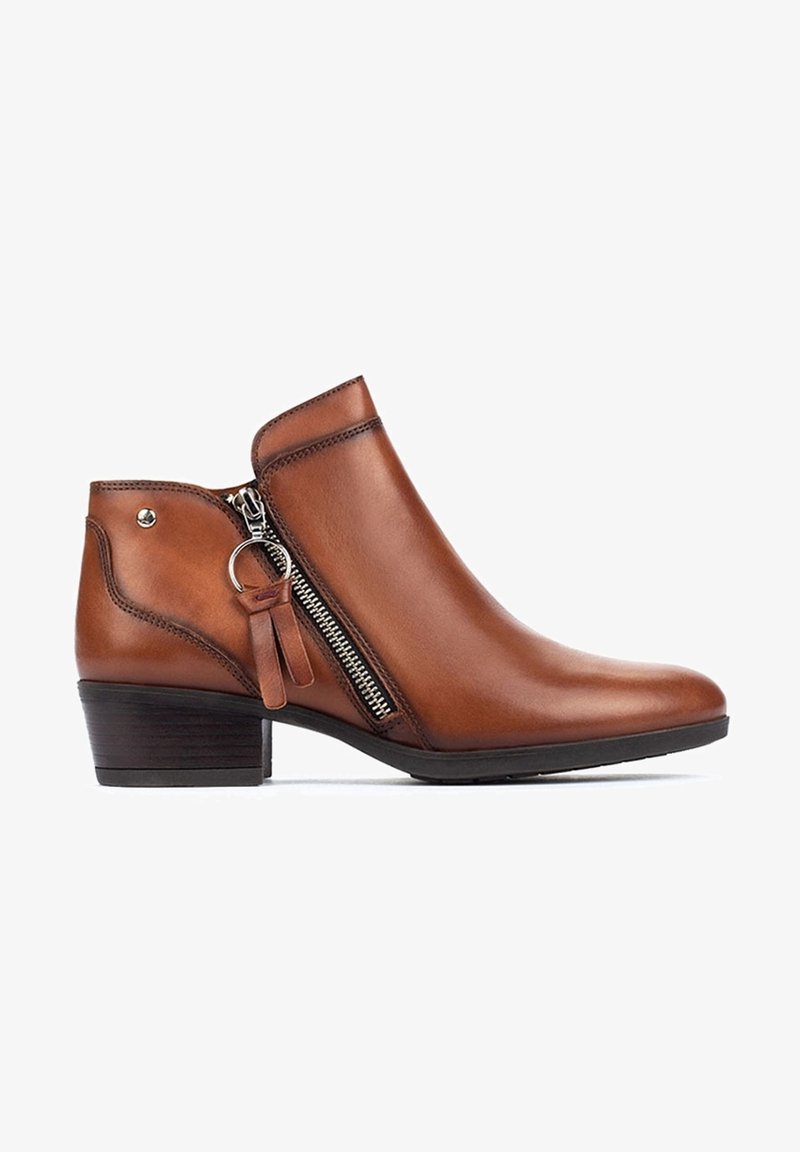 Bottines en cuir marron avec une fermeture éclair latérale, un petit talon et un pompon décoratif, avec une texture lisse et un design élégant.