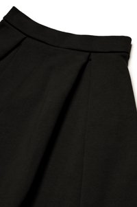 Sort plisseret nederdel med en glat tekstur og et bredt taljebånd, prydet med pænt syede sømme for holdbarhed og designstruktur.