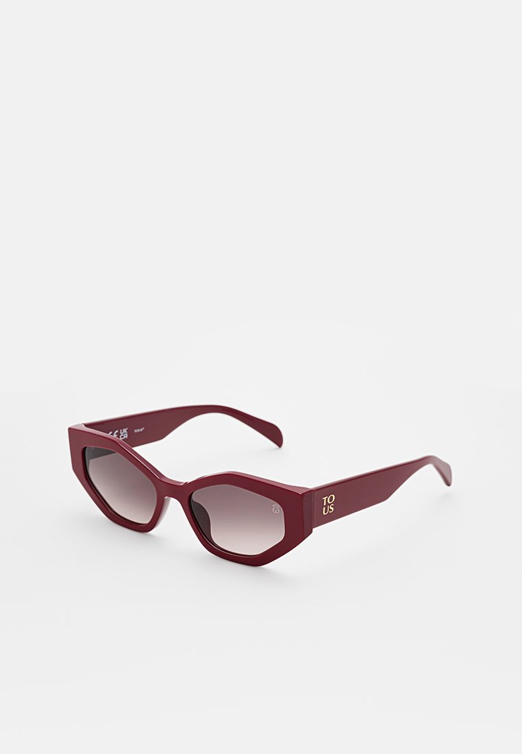 Bordowe okulary w kształcie kociego oka z gradientowymi soczewkami. Matowe wykończenie szerokich zauszników z złotym brandingiem "TO US". Kątowy design.