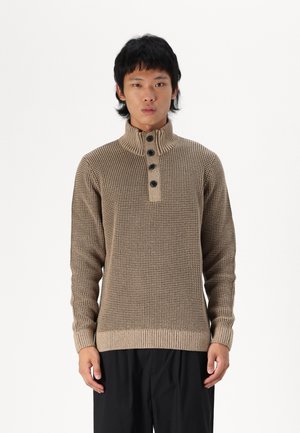 Jersey de punto marrón con un cuello alto, tres botones negros y puños y dobladillo de canalé. Patrón texturizado en toda la tela.