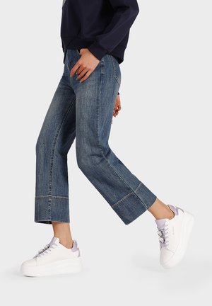 Culotte in denim con taglio cropped, colore blu, sneakers platform bianche con dettagli in lavanda e laccio, vista laterale.