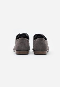 Gray suede shoes with a low profile, rounded toe, and wooden heel accents. Detailed stitching along the edges and a textured finish.