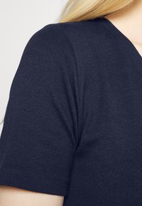 T-shirt de manga curta azul marinho, feito de um tecido leve e suave, com decote em V e um acabamento texturizado discreto.