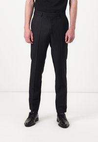 Pantaloni neri a righe sottili con una vestibilità su misura, caratterizzati da fronte piatto, passanti per cintura e una texture liscia. Abbinati a scarpe eleganti nere.