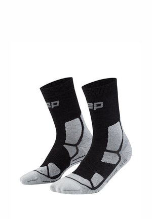 Black and gray crew socks with cushioned areas on heel, toe, and arch, featuring a ribbed cuff and partial brand lettering near the top.