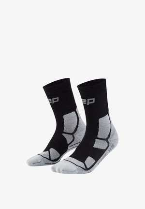 Black and gray crew socks with cushioned areas on heel, toe, and arch, featuring a ribbed cuff and partial brand lettering near the top.