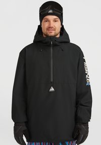 Zwarte pullover jacket met capuchon, voorzien van een voorkant rits en een driehoekig logo. Vergezeld van zwarte handschoenen en gebloemde broek.