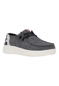 Zapato informal de tela gris oscuro con cordones negros, suela de goma blanca y un panel trasero con diseño. Presenta un pequeño logo en la lengua.
