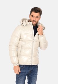 Giacca imbottita grigia chiara con finitura lucida, dotata di cappuccio, cerniera frontale e tasche laterali. Tessuto texturizzato con design trapuntato.