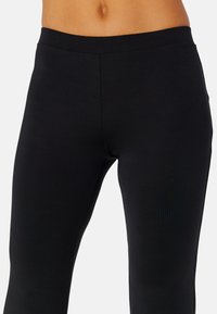 Leggings neri realizzati in un tessuto elasticizzato, dotati di una vita alta e di una texture liscia, senza motivi o decorazioni visibili.