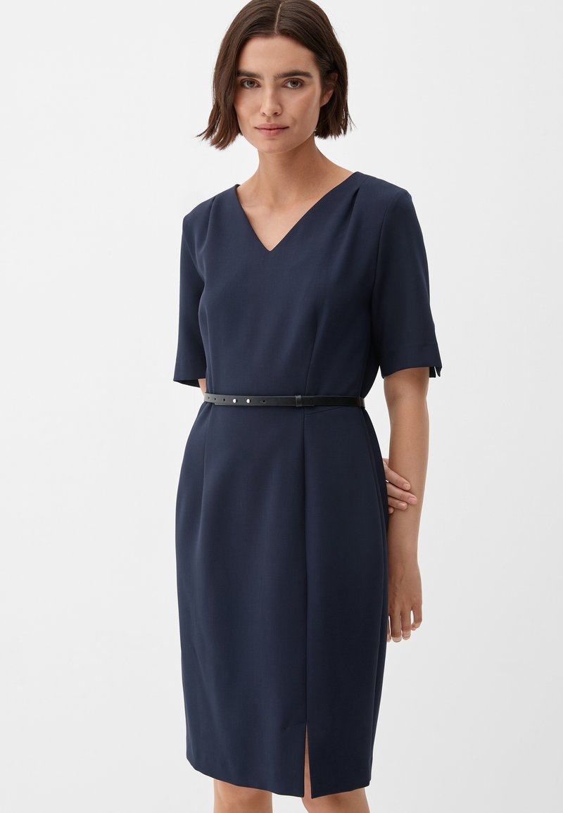 Donkerblauwe jurk met een V-hals, korte mouwen en een zwarte riem op de taille. Voorzien van een zijsplit en een gladde stoftextuur.