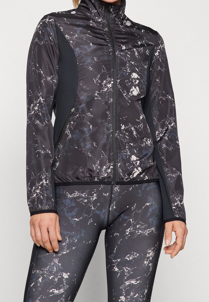 Černá sportovní bunda s mramorovým vzorem, vysokým límcem, plným zipem a kontrastními černými bočními panely; přiléhavý střih a elastické manžety.