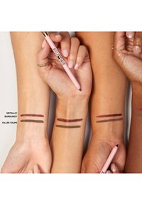 Ein Set von drei Armfarben mit zwei Brauntönen, die als "Metallic Burgunder" und "Killer Taupe" beschriftet sind. Ein rosa Bleistift mit goldenen Akzenten wird gehalten.