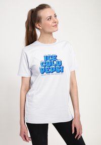 Bílý bavlněný tričko s nápisem "ICE COLD PEPSI" velkým modrým písmem a sněhovými akcenty. Krátké rukávy a volnější střih.