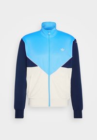 Färgblockerad träningsjacka med dragkedja framtill; har ljusblå, marinblå och cremefärgade paneler, elastiska muddar och sidfickor.