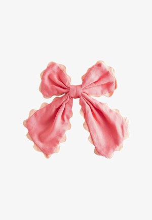 Pink fabric bow with scalloped edges, tied in a loose, double-looped style on a white background.