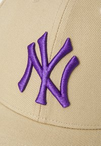 Bežna bejzbol kapa s istaknutim ljubičastim izvezenim "NY" logom. Tkanina ima glatku teksturu s vidljivim detaljima šivanja.