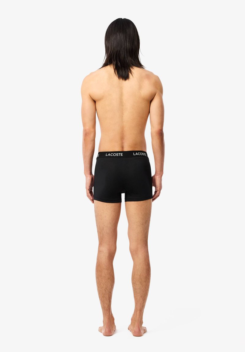 Boxer-briefs noirs avec une taille souple affichant le logo "LACOSTE", fabriqués en matériau en coton extensible, design ajusté vu de dos.